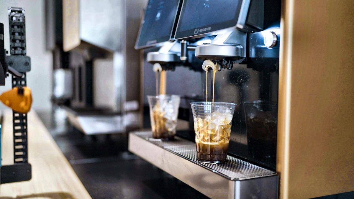 The robot pulling two shots into cups at the bar
