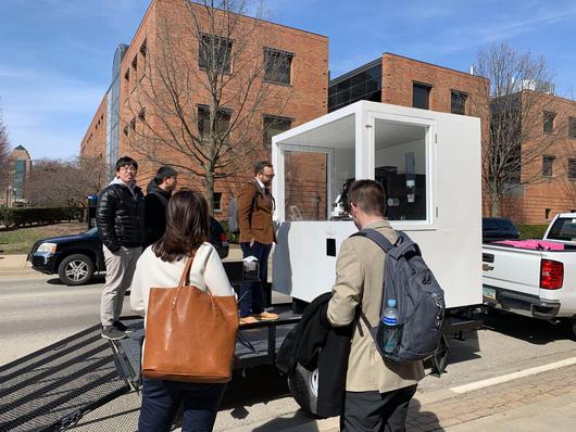 Early Yummy Future kiosk built on a trailer, parked on the UIUC campus with people gathered around it